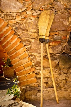 Two old fashioned brooms, a brick arch and a stone wall in Mexico