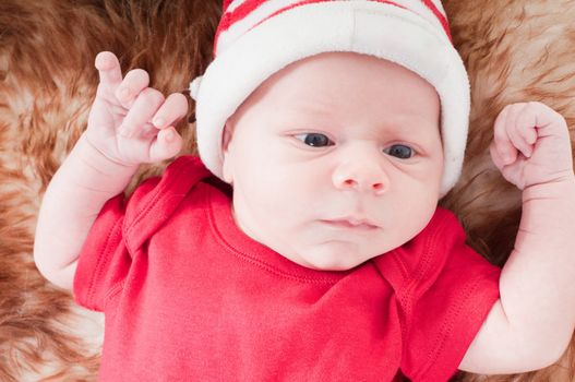 Newborn baby in chritstmas hat lies on fur