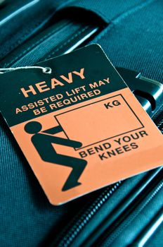 Luggage - black trolley - tagged with HEAVY sign