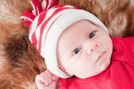 Newborn baby in chritstmas hat lies on fur