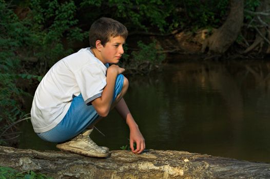 Teenage boy crossing river on a log
