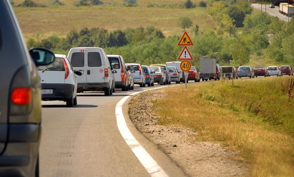 maintains on country road in Serbia, slow moving cars row and traffic signs