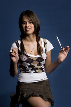 Young woman in mini skirt, sitting on a stool, with glasses and pen in her hand, trying to figure out what is going on in the distance