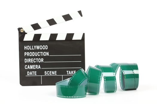 Movie clapper board and film roll over white 