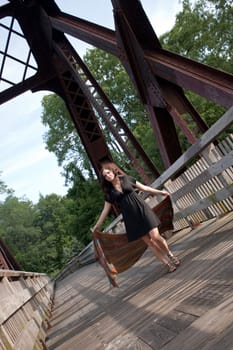 A carefree brunette girl walking along a bridge with a scarf blowing in the breeze.