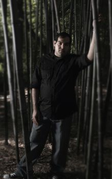 A man standing in a dark bamboo forest