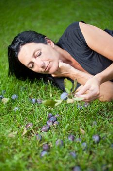 woman eating a plum on a meadow