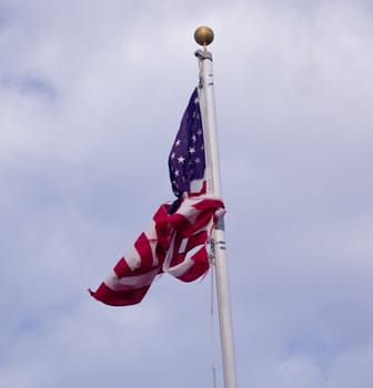 Unusual picture of US stars and stripes flag tied into a knot against the flag pole and torn