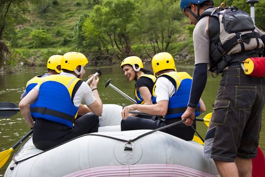 Group of young people sitting in a boat, getting ready for whitewater rafting