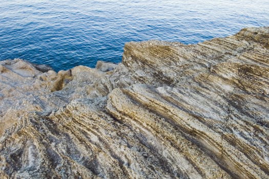 dry and polished by wind old rock and blue ocean water background