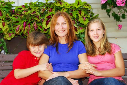 Family of mother and children sitting in front of their house