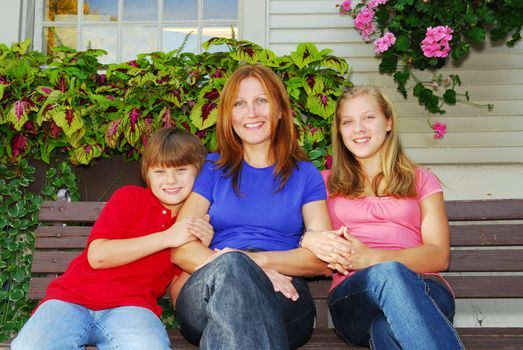 Family of mother and children sitting in front of their house