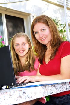 Mother and daughter working on a portable computer at home in the garden