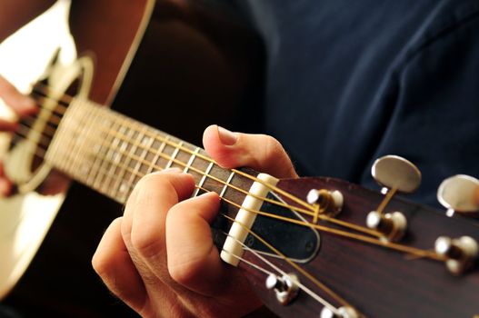 Hands of a person playing an acoustic guitar close up