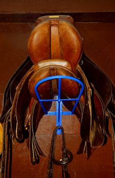 Two saddles on a rack in a tack room, horseback riding equipment