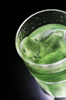 green cocktail with ice over black color