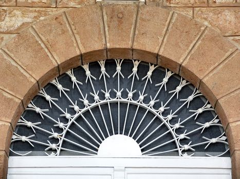 semicircular vintage window with decorative iron guards