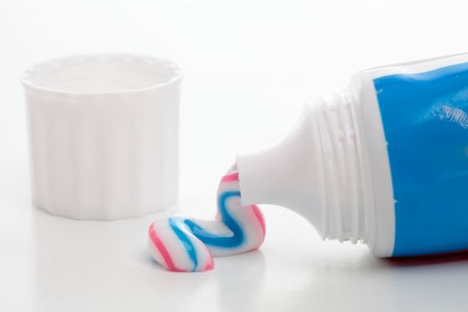 Toothpaste white blue red stripe queezed from a tube on a white background.