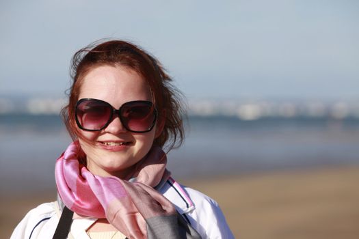 The happy girl in solar glasses on a beach