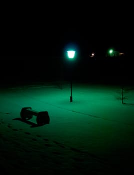 Light from lantern illuminates bench in the park.