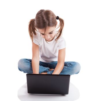 Little girl sitting on floor working with a laptop