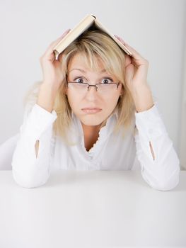 blond girl in glasses hidden under a book
