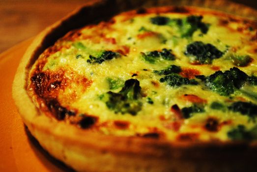 A plate of quiche with broccoli.
