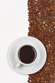 Coffee in white cup on saucer placed on background of cofee beans and white