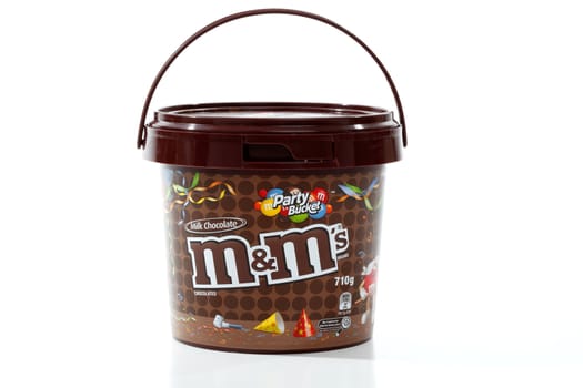 M&M's party bucket 710g of sweet colourful button shaped candy coated chocolate confectionary.  Made by Mars Inc, since 1941.  White background, editorial use only.