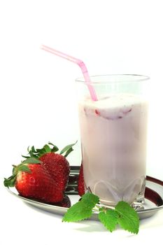 Milk shake with strawberries and lemon balm on white background