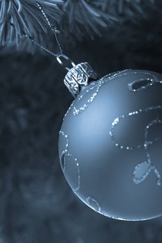 Christmas toy on a branch of a fur-tree blue tone. A glass sphere isolated on a white background
