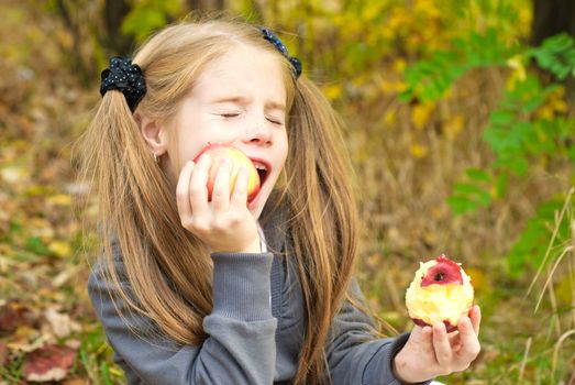 Little girl eating apple outdoors