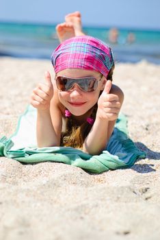 Happy little girl in sunglasses on the beach