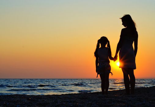 Mother and daughter walking on the beach