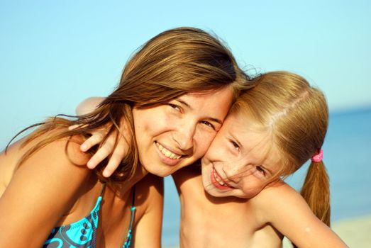 Happy smiling young mother with her daughter on the beach