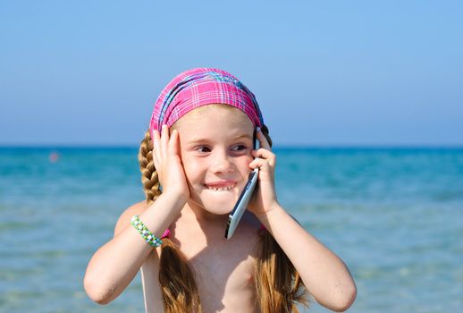 A little girl talking mobile phone on the beach