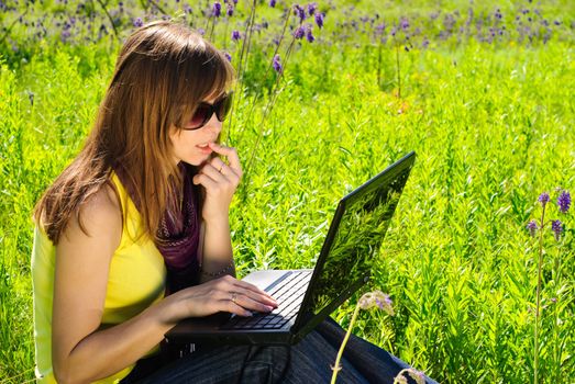 Young beautiful woman with laptop outdoor. Sunny summer day.