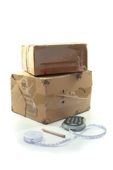 Cartons with pen, calculator and measuring tape on white background