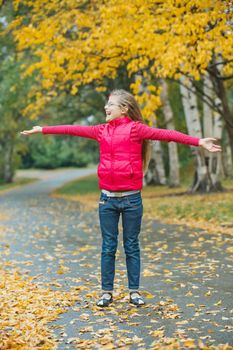 Cute girl walking in the autumn park. Rain, yellow leaves, tree.