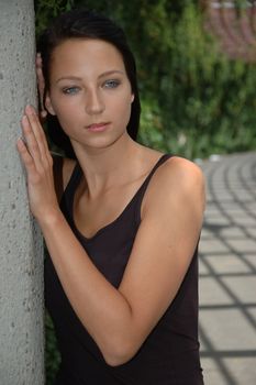 Female model portrait. Girl standing near column, wearing casual clothes.