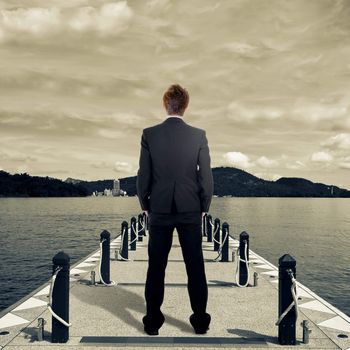 Business man standing on dock near lake.