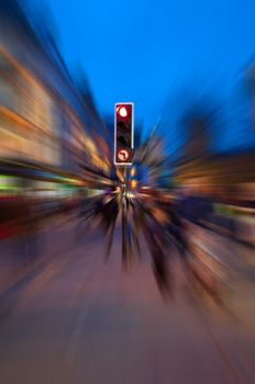 A traffic light surrounded by radial motion blur giving a chaotic concept to an evening urban street.