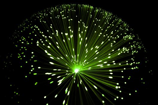 Abstract style overhead view of illuminated fiber optic strands against black.