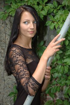 Female model holding handrail. Pretty Polish girl posing in front of green leaves.