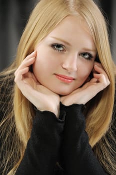 Portrait of the pretty young girl of the blonde. On a black background