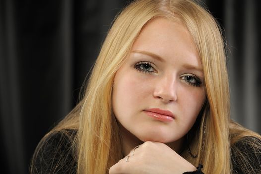 Portrait of the pretty young girl of the blonde. On a black background