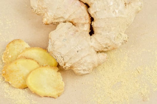 Fresh, dried and powdered ginger at brown background