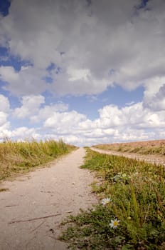 Closeup of rural gravel road under amazing cloudy sky.