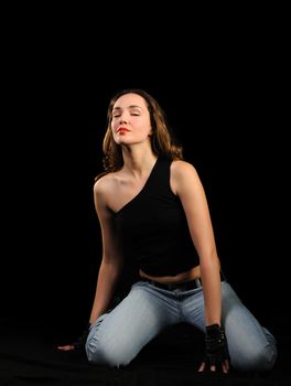 The beautiful woman on a black background. Jeans and black blouse