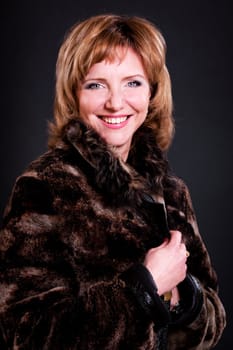 middle-aged woman in a fur coat on black